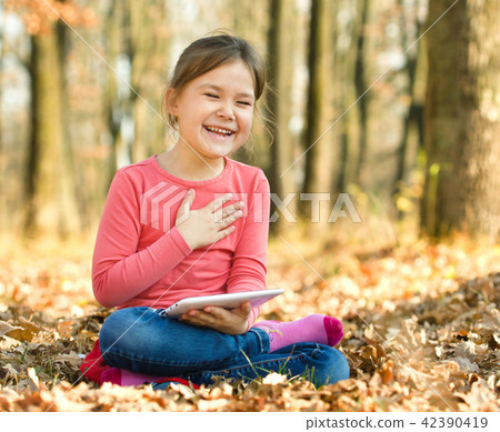Little girl is reading a book outdoors Little girl is reading a book outdoors 42390419