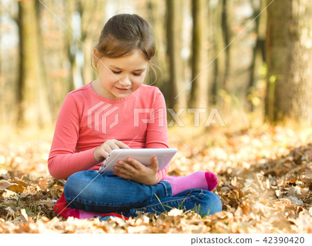 Little girl is reading from tablet Little girl is reading from tablet 42390420