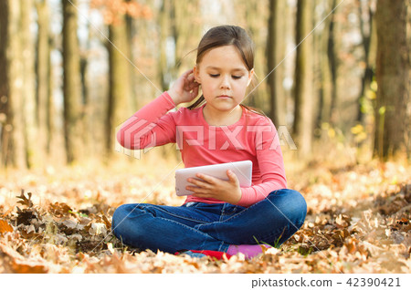 Little girl is reading a book outdoors Little girl is reading a book outdoors 42390421