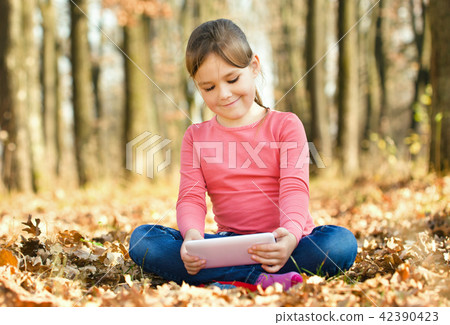 Little girl is reading from tablet Little girl is reading from tablet 42390423