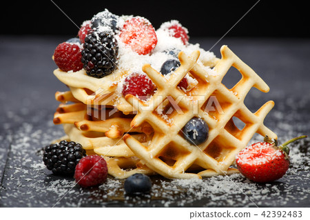 Photo of viennese wafers with fresh raspberries, strawberries sprinkled with powdered sugar on 42392483