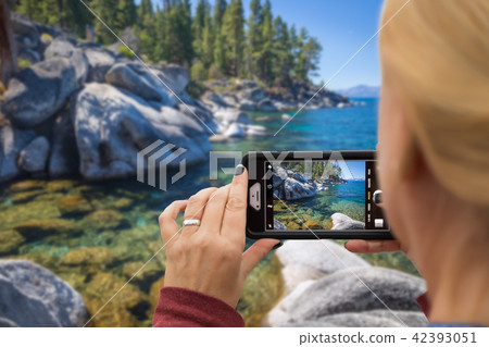 Woman Taking A Beautiful Lake Picture with Her Smart Phone Woman Taking A Beautiful Lake Picture with Her Smart Phone 42393051