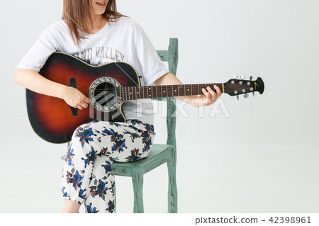 A girl sitting in a chair and playing a guitar 42398961