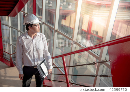 Asian engineer holding files at construction site 42399750