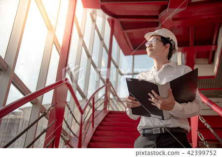 Asian engineer holding files at construction site 42399752
