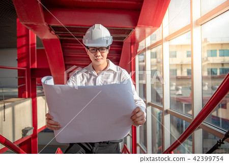 Engineer holding blueprints at construction site 42399754