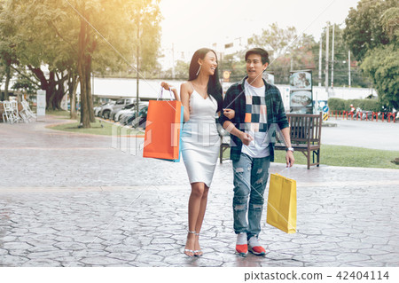 Asian couple walking at street holding shopping Asian couple walking at street holding shopping 42404114