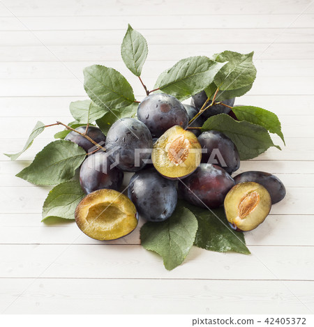 Fresh plum fruit with leaves on a light table Fresh plum fruit with leaves on a light table 42405372