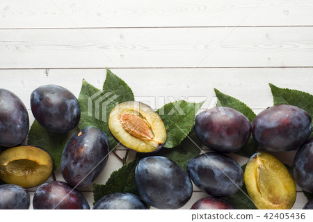 Fresh plum fruit with leaves on a light table 42405436