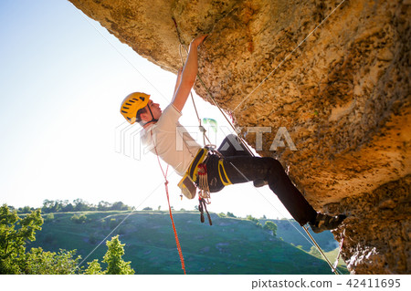 Image of tourist man in helmet clambering up Image of tourist man in helmet clambering up 42411695