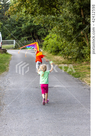 Boy and girl having fun flying a kite in summer Boy and girl having fun flying a kite in summer 42412598