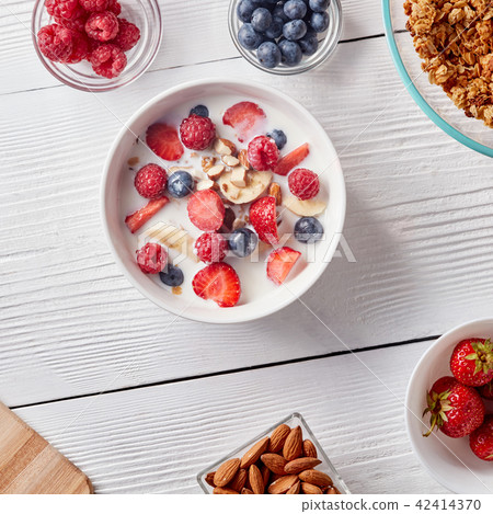 Ingredirnts for preparing healthy organic breakfast - granola, strawberries, honey, banana in white Ingredirnts for preparing healthy organic breakfast - granola, strawberries, honey, banana in white 42414370