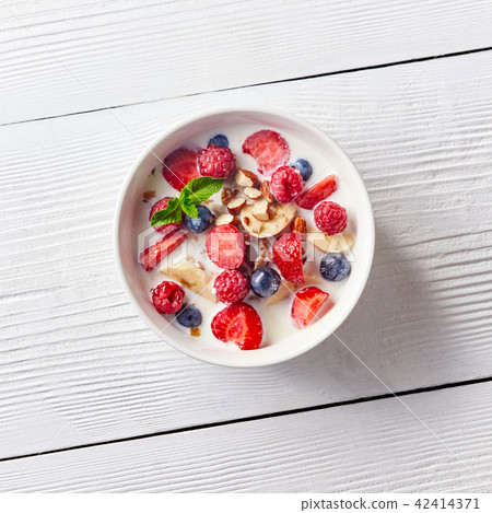 Colorful and tasty ready breakfast from corn muesli, berries, milk, almonds, slices banana on a bowl Colorful and tasty ready breakfast from corn muesli, berries, milk, almonds, slices banana on a bowl 42414371