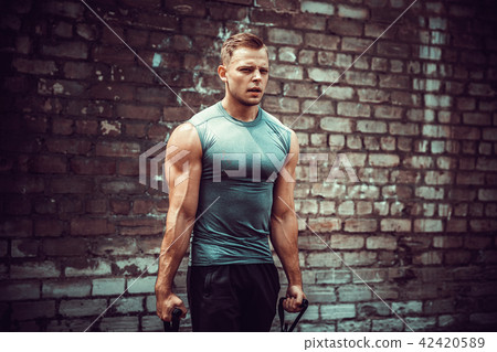 Fitness man exercising with stretching band in outdoor gym. 42420589