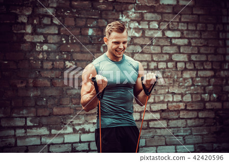 Fitness man exercising with stretching band in outdoor gym. 42420596