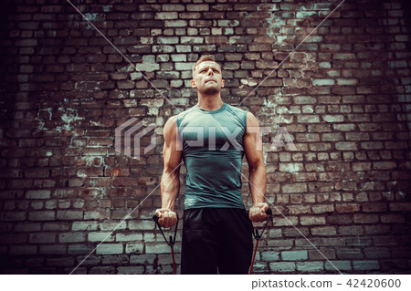 Fitness man exercising with stretching band in outdoor gym. 42420600