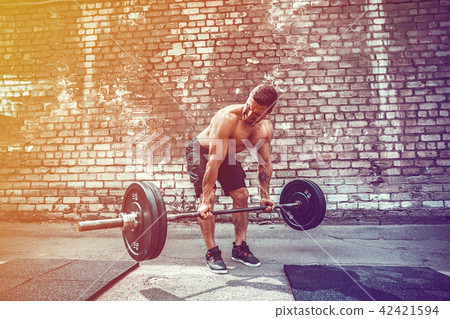 Athletic man working out with a barbell. Strength and motivation. Exercise for the muscles of the Athletic man working out with a barbell. Strength and motivation. Exercise for the muscles of the 42421594