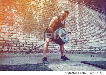 Athletic man working out with a barbell. Strength and motivation. Exercise for the muscles of the 42422158