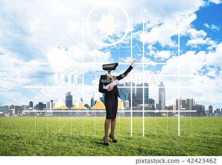 Camera headed woman standing on green grass against modern cityscape Camera headed woman standing on green grass against modern cityscape 42423462