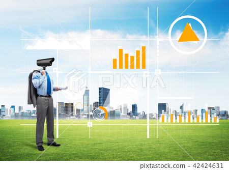 Camera headed man standing on green grass against modern cityscape Camera headed man standing on green grass against modern cityscape 42424631