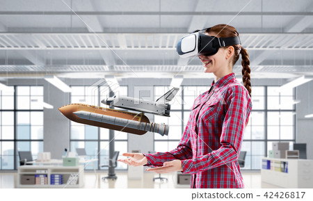 Girl in checked shirt wearing VR glasses experiencing another reality. Mixed media Girl in checked shirt wearing VR glasses experiencing another reality. Mixed media 42426817