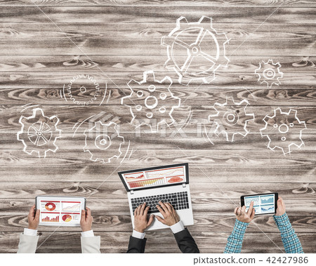 Top view of businesspeople sitting at table and using gadgets Top view of businesspeople sitting at table and using gadgets 42427986