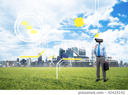 Camera headed man standing on green grass against modern cityscape Camera headed man standing on green grass against modern cityscape 42428142