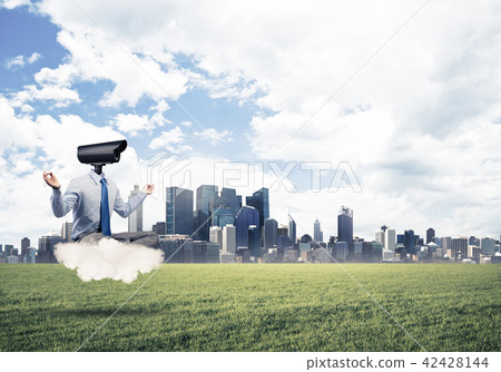 Camera headed man sitting in lotus pose on cloud against modern cityscape Camera headed man sitting in lotus pose on cloud against modern cityscape 42428144