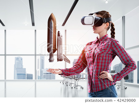 Girl in checked shirt wearing VR glasses experiencing another reality. Mixed media Girl in checked shirt wearing VR glasses experiencing another reality. Mixed media 42429000