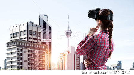 Girl in checked shirt wearing VR glasses experiencing another re Girl in checked shirt wearing VR glasses experiencing another re 42430765