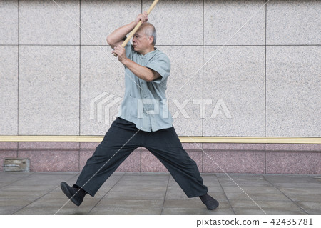 Martial artist practicing Taiji stick 42435781