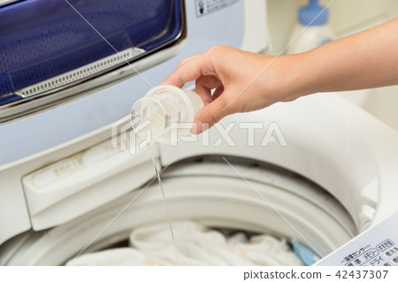 把洗滌劑放的婦女在洗衣機 把洗滌劑放的婦女在洗衣機 42437307