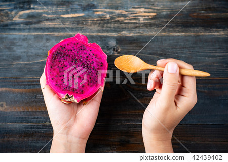 Hand holding half red dragon fruit and spoon Hand holding half red dragon fruit and spoon 42439402