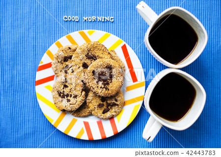 Oatmeal cookies with chocolate on blue napkin and two cups of coffee, good morning inscription Oatmeal cookies with chocolate on blue napkin and two cups of coffee, good morning inscription 42443783