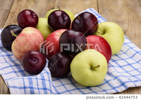 Fresh apples and plums on wooden table 42444753