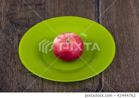 Red apple in a green plate on a wooden table Red apple in a green plate on a wooden table 42444762