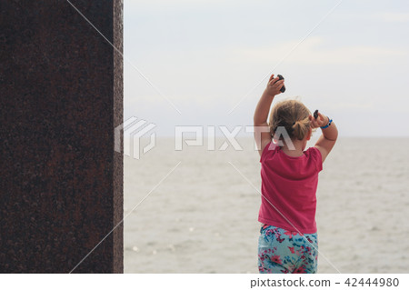 Cute little girl throwing the stones in the sea. 42444980