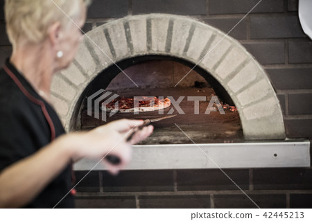 Women are putting the pizza 42445213