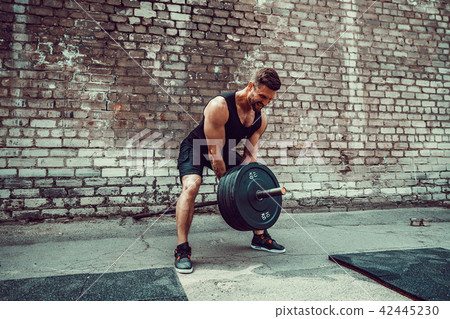 Athletic man working out with a barbell. Strength and motivation. Exercise for the muscles of the Athletic man working out with a barbell. Strength and motivation. Exercise for the muscles of the 42445230