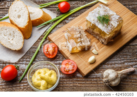 Homemade jelly meat with mustard, bread, tomatoes and garlic on the table. Holodets 42450103