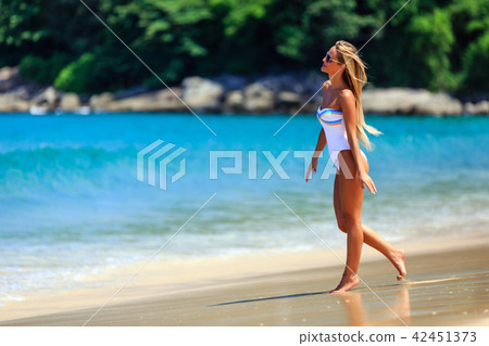 Model in white swimsuit walking at the beach 42451373