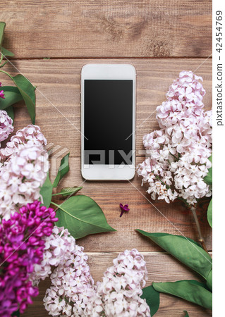 Bouquet of lilac flowers on wooden planks with mobile phone. 42454769
