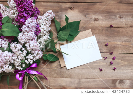Bouquet of lilac flowers on wooden planks with blank card for text . Top view Bouquet of lilac flowers on wooden planks with blank card for text . Top view 42454783