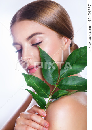 Beautiful woman face portrait with green leaf concept for skin care or organic cosmetics. Studio Beautiful woman face portrait with green leaf concept for skin care or organic cosmetics. Studio 42454787