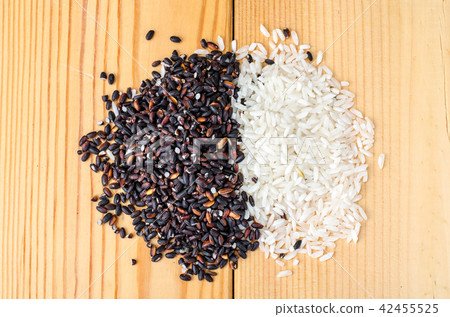 Grains of white and black rice on wooden table 42455525