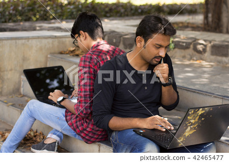 Young students using laptop, smartphone in park Young students using laptop, smartphone in park 42465477
