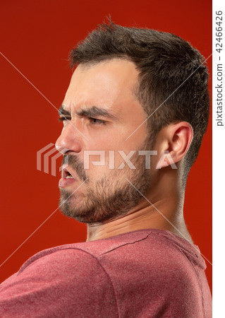 The young emotional angry man screaming on red studio background The young emotional angry man screaming on red studio background 42466426