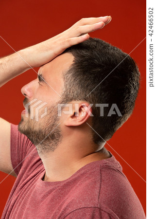 Beautiful man looking suprised and bewildered isolated on red 42466502
