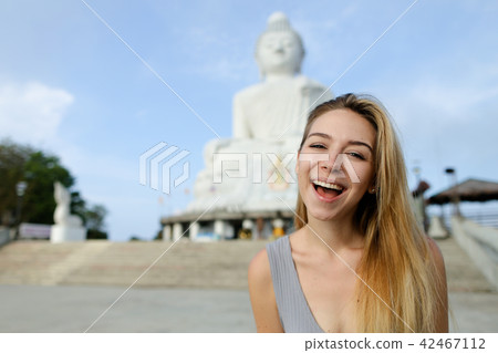 Young smiling girl standing with Buddha statue in Phuket, Thailand. Young smiling girl standing with Buddha statue in Phuket, Thailand. 42467112