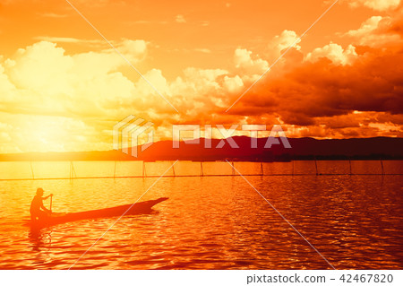 Silhouette man in the wooden boat with sunset 42467820